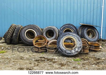 A row of used tires and parts sits with a stack of rusty old rims in a scrap heap at an industrial work site; Port McNeill, British Columbia, Canada View Large Photo Image Stock Photo - A row of used tires and parts sits with a stack of rusty old rims in a scrap heap at an industrial work site; Port McNeill, British Columbia, Canada. Fotosearch
