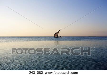 Stock Image - A sailboat in the distance on the tranquil water of the Indian Ocean; Vamizi Island, Mozambique. Fotosearch