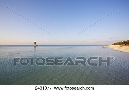 A sailboat in the distance on the tranquil water of the Indian Ocean; Vamizi Island, Mozambique View Large Photo Image Stock Photo - A sailboat in the distance on the tranquil water of the Indian Ocean; Vamizi Island, Mozambique. Fotosearch