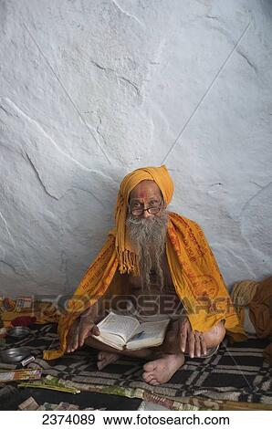 Stock Photo - A senior man sits reading a book; Hampi, Karnataka, India. Fotosearch