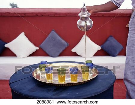 Stock Image - A Server Pouring Tea From A Silver Teapot. Fotosearch