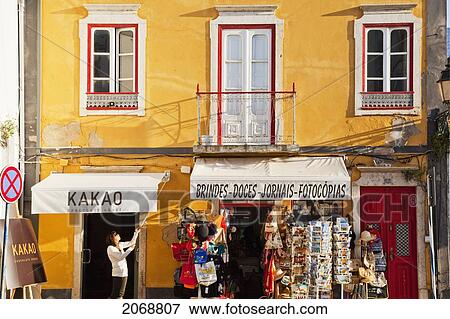 Stock Photo - A Shop Owner Lifts The Awning Over The Displays Outside The Front Of The Shop; Faro Algarve Portugal. Fotosearch