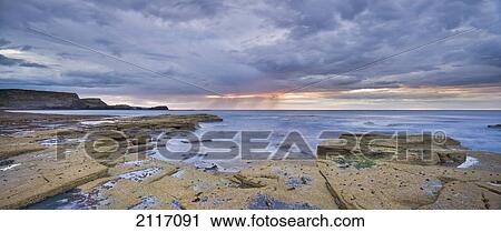 Stock Image - A Showery Evening At Low Tide In Saltwick Bay; Saltwick Bay North Yorkshire England. Fotosearch
