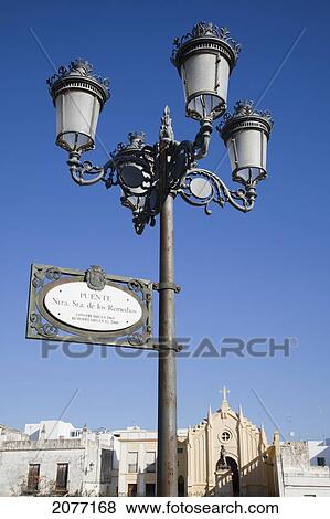 A Sign On A Lamp Post With A Church In The Background; Chiclana De La Frontera Andalusia Spai View Large Photo Image Stock Photo - A Sign On A Lamp Post With A Church In The Background; Chiclana De La Frontera Andalusia Spai. Fotosearch