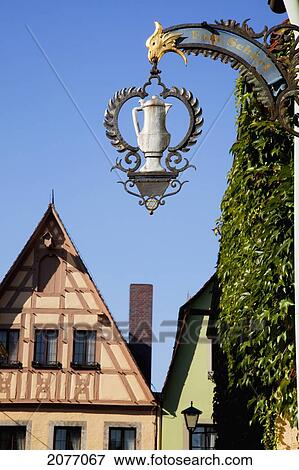 Stock Photo - A Silver Coffee Pot On A Hanging Sign Against A Blue Sky; Rothenburg Ob Der Tauber Bavaria Germany. Fotosearch