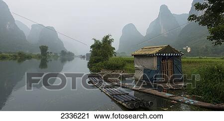 Stock Image - A Small Building And Boats Along The Shoreline Of The Yulong River; Guilin, Guangxi, China. Fotosearch
