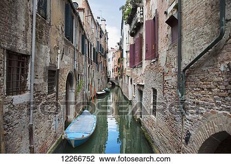 Stock Image - A small canal with boats; Venice, Italy. Fotosearch