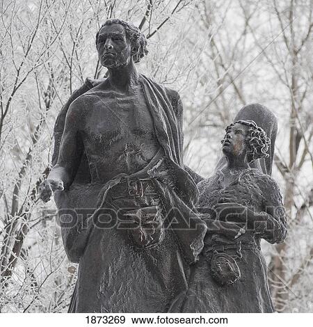 Stock Photo - A Stone Statue Of A Man And Child In Winter; Winnipeg, Manitoba, Canada. Fotosearch