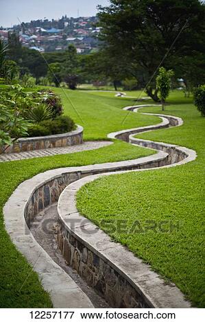 Stock Photo - A stone walled path winding through gardens; Kigali, Rwanda. Fotosearch