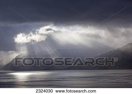 Stock Image - A stormy sky breaks above the Arnarfjorour fjord at sunset; Westfjords, Iceland. Fotosearch