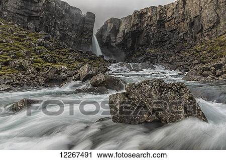 A stream flows over a small waterfall and flows past a rock on the East fjords of Iceland; Iceland View Large Photo Image Stock Image - A stream flows over a small waterfall and flows past a rock on the East fjords of Iceland; Iceland. Fotosearch