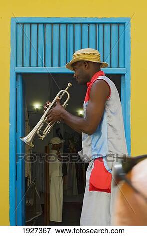 Stock Photo - A Street Entertainer Playing A Trumpet Beside Colorful Doorway, Havana, Cuba. Fotosearch