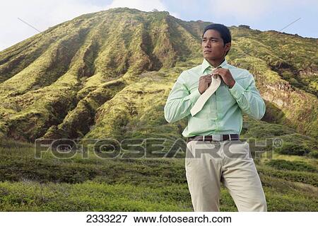 Stock Photo - A stylish businessman in front of Hawaiian mountain terrain; Oahu, Hawaii, United States of America. Fotosearch