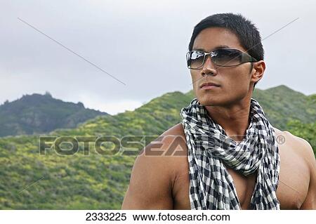 Stock Photography - A stylish man wearing sunglasses and a scarf; Hawaii, United States of America. Fotosearch