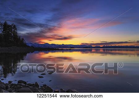 A summer sunset colours the sky adjacent to Lynn Canal, Inside Passage, Chilkat Mountains beyond in the distance; Alaska, United States of America View Large Photo Image Picture - A summer sunset colours the sky adjacent to Lynn Canal, Inside Passage, Chilkat Mountains beyond in the distance; Alaska, United States of America. Fotosearch