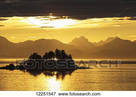 A summer sunset colours the sky adjacent to Lynn Canal, with Chilkat Mountains in the distance; Alaska, United States of America View Large Photo Image Stock Photo - A summer sunset colours the sky adjacent to Lynn Canal, with Chilkat Mountains in the distance; Alaska, United States of America. Fotosearch