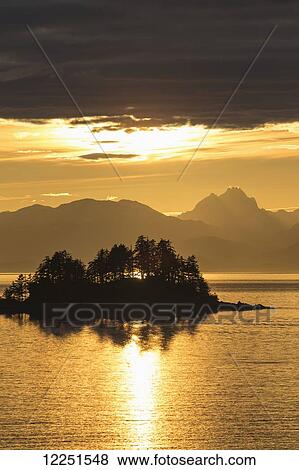 Stock Photo - A summer sunset colours the sky adjacent to Lynn Canal, with Chilkat Mountains in the distance; Alaska, United States of America. Fotosearch