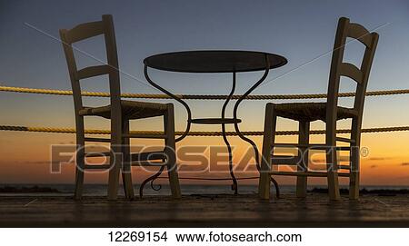 A table and chairs on a patio with a view of a colourful sunset; Paphos, Cyprus View Large Photo Image Picture - A table and chairs on a patio with a view of a colourful sunset; Paphos, Cyprus. Fotosearch