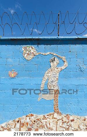 Stock Image - A Tile Mosaic Of A Human Figure Holding A Net And A Butterfly On A Blue Wall; Guatemala City Guatemala. Fotosearch
