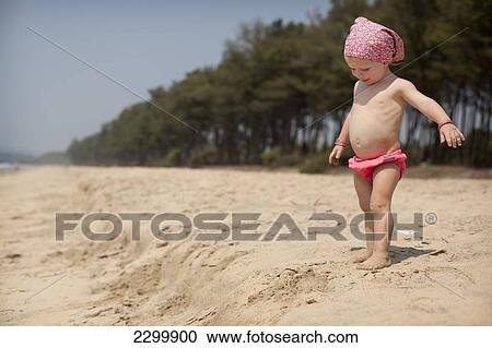 Stock Image - A toddler wearing waterproof nappy pants, plays on Turtle Beach, Goa, India.. Fotosearch