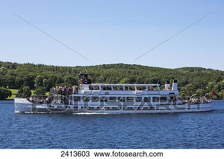 Stock Image - A tour boat full of people on a lake; Lake District, Cumbria, England. Fotosearch
