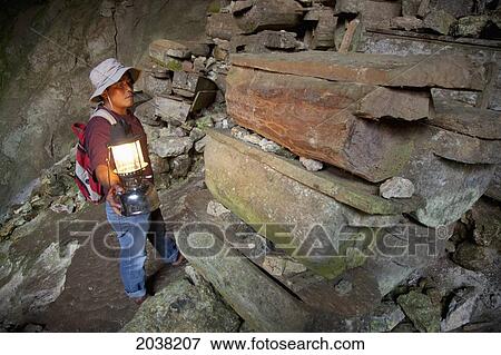 A Tour Guide Uses A Lantern To Look At The Many Coffins In The Entrance To Lumiang Burial Cave Near Sagada; Luzon Philippines View Large Photo Image Stock Photo - A Tour Guide Uses A Lantern To Look At The Many Coffins In The Entrance To Lumiang Burial Cave Near Sagada; Luzon Philippines. Fotosearch