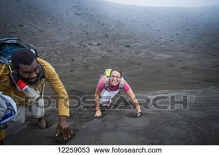 Stock Image - A tourist climbing to the rim of Yasur Volcano with a local guide; Tanna Island, Vanuatu. Fotosearch
