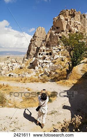 Stock Image - A tourist photographs Uchisar Castle; Uchisar, Cappadocia, Turkey. Fotosearch