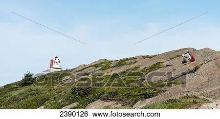 A tourist sits on a hill overlooking the atlantic ocean and Cape Spear with a lighthouse in the distance; St. John's, Newfoundland and Labrador, Canada View Large Photo Image Stock Photograph - A tourist sits on a hill overlooking the atlantic ocean and Cape Spear with a lighthouse in the distance; St. John's, Newfoundland and Labrador, Canada. Fotosearch