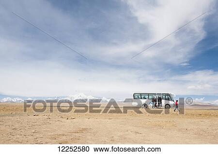 Stock Image - A tourist walking by a tourist bus on Tibetan Friendship Highway; Tibet, China. Fotosearch