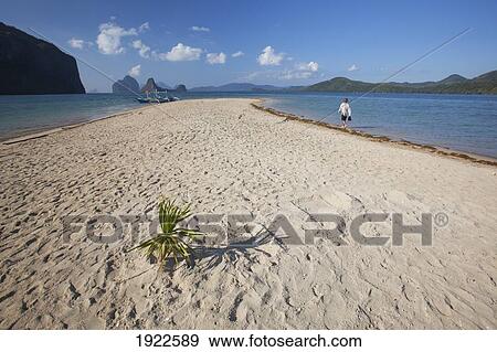 Stock Photo - A Tourist Walks Along A White Sand Island Near El Nido; Bacuit Archipelago, Palawan, Philippines. Fotosearch
