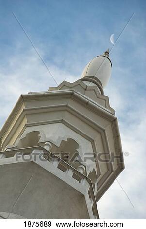 Stock Photo - A Tower With An Ornate Facade With The Moon In The Sky; Kuala Lumpur, Malaysia. Fotosearch