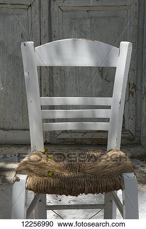 Stock Image - A traditional taverna chair with painted wood and rush seat; Mykonos Town, Mykonos, Cyclades, Greek Islands, Greece. Fotosearch