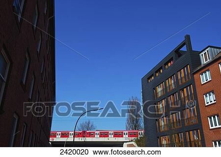 A train going over an elevated track and a brick residential building with blue sky; Hamburg, Germany View Large Photo Image Stock Image - A train going over an elevated track and a brick residential building with blue sky; Hamburg, Germany. Fotosearch