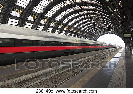 Stock Photography - A train on the tracks in a train station with domed ceiling; Milan, Lombardy, Italy. Fotosearch