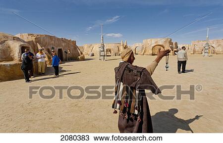 Stock Image - A Tunisian Man Displays His Souvenirs At The Old Star Wars Set Mos Espa; Chot El Jerrid, Tunisia, North Africa. Fotosearch