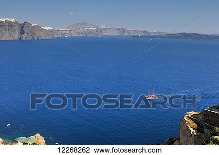 Stock Image - A two-masted sailing ship plies the caldera of Santorini Island; Santorini, Greece. Fotosearch