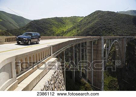 Stock Image - A vehicle on an elevated road going through a mountainous landscape; California, United States of America. Fotosearch