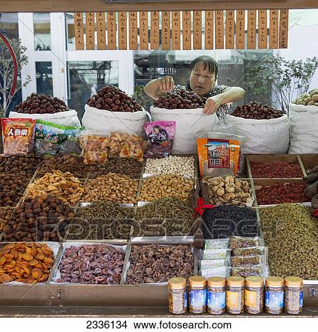 A Vendor At Her Market Stand With Dried Fruit And Nuts; Jiuquan, Gansu, China View Large Photo Image Picture - A Vendor At Her Market Stand With Dried Fruit And Nuts; Jiuquan, Gansu, China. Fotosearch