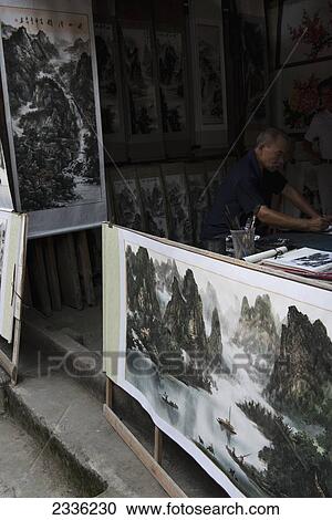 Stock Image - A Vendor With Artwork On Display; Yangshuo, Guangxi, China. Fotosearch