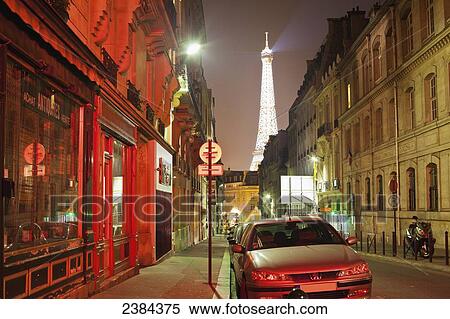 Stock Photography - A view down a street with the glowing Eiffel Tower at nighttime; Paris, France. Fotosearch