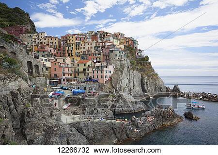 Stock Image - A view of Manarola with clear blue ocean and colourful buildings; Manarola, Liguria, Italy. Fotosearch