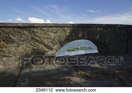 Stock Image - A Wall With An Arched Window With A View Of Lake Maggiore; Isole Di Brissago, Ticino, Switzerland. Fotosearch