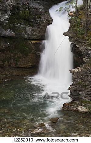 A waterfalls cutting into rock cliffs; Waterton, Alberta, Canada View Large Photo Image Stock Image - A waterfalls cutting into rock cliffs; Waterton, Alberta, Canada. Fotosearch