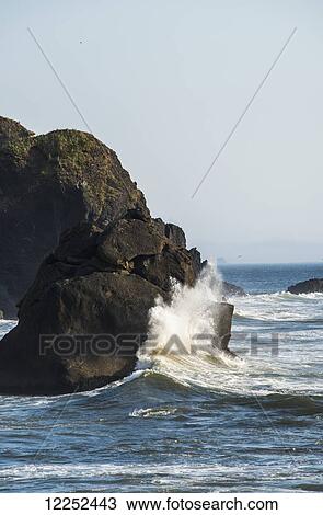 Stock Image - A wave hits a rock at Ecola State Park; Cannon Beach, Oregon, United States of America. Fotosearch
