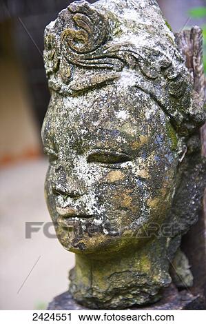 Stock Image - A weathered stone carving of a woman's face; Ulpotha, Embogama, Sri Lanka. Fotosearch