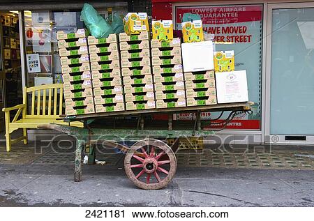 Stock Image - A weathered wooden cart outside a shop window filled with boxes in Soho; London, England. Fotosearch