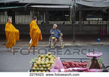 A wheelchair bound beggar watches a group of Buddhist monks on their morning alms round; Bangkok, Thailand View Large Photo Image Stock Image - A wheelchair bound beggar watches a group of Buddhist monks on their morning alms round; Bangkok, Thailand. Fotosearch