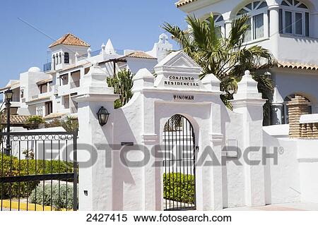 Stock Photography - A white gated entrance and whitewash buildings; Chiclana de la Frontera, Andalusia, Spain. Fotosearch