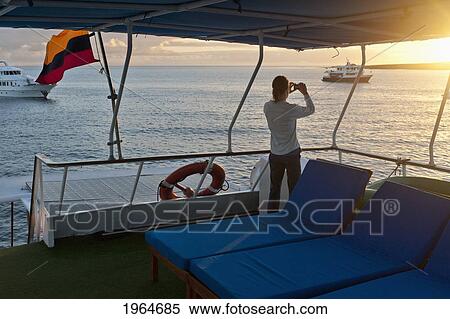 A Woman Aboard A Boat Looks Out Over The Water With A Camera; Punta Suarez Galapagos Equador View Large Photo Image Stock Photography - A Woman Aboard A Boat Looks Out Over The Water With A Camera; Punta Suarez Galapagos Equador. Fotosearch